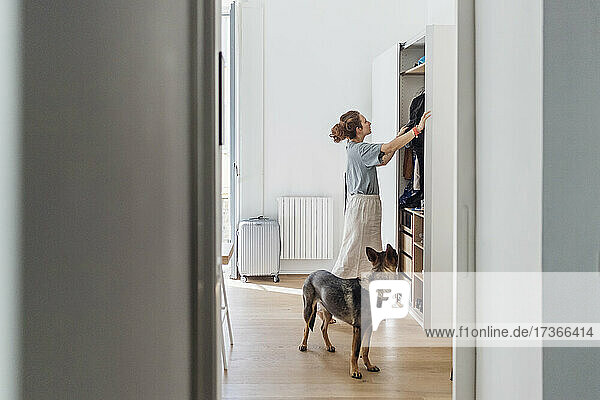 Woman looking at closet while standing by dog in apartment