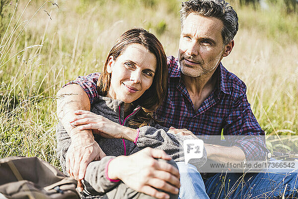 Couple sitting together at meadow during sunny day