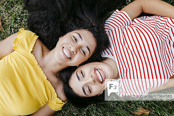 Glückliches lesbisches Paar  das zusammen auf dem Rasen eines Parks liegt