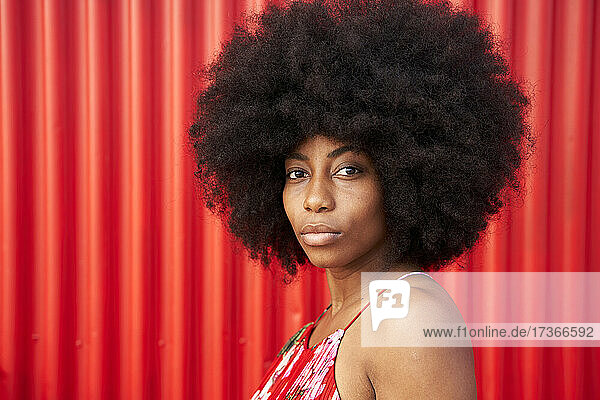 Afro young woman by red corrugated wall