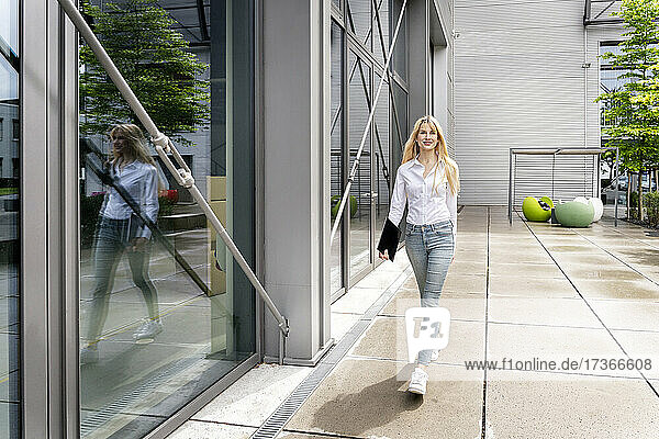 Junge Frau  die an einem Bürogebäude vorbeigeht