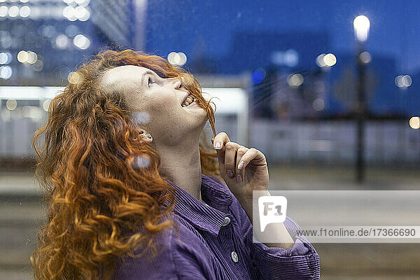 Smiling redhead woman looking up at tram station
