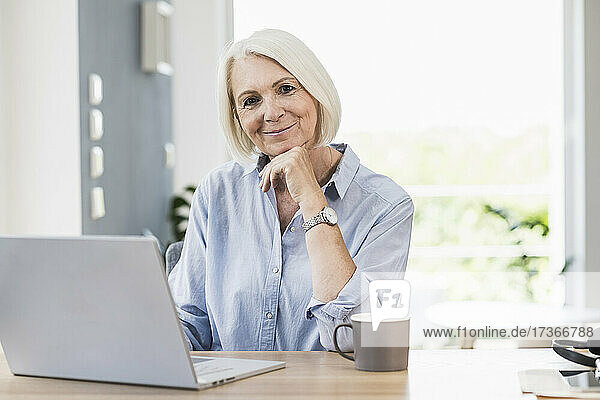 Businesswoman with hand on chin at desk in home office