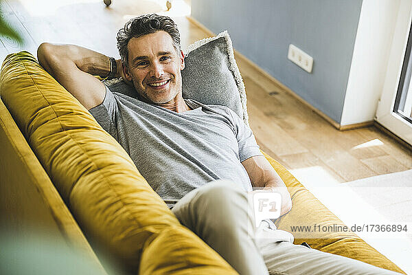 Lächelnder Mann entspannt sich auf dem Sofa zu Hause