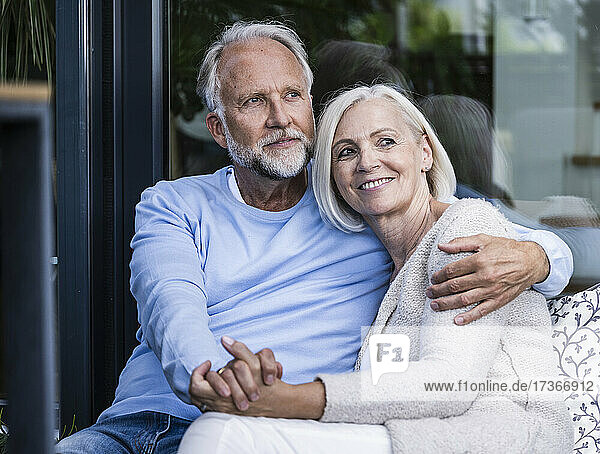 Mature couple holding hands while sitting at balcony