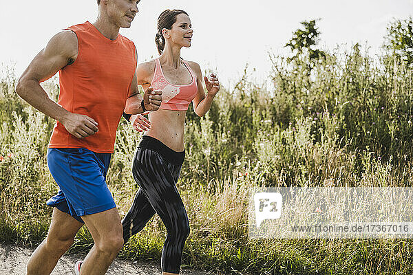 Männliche und weibliche Athleten laufen gemeinsam durch eine Wiese