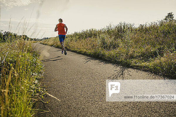 Mature man running on road during sunny day