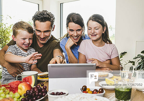 Smiling family gesturing during video call on laptop at home