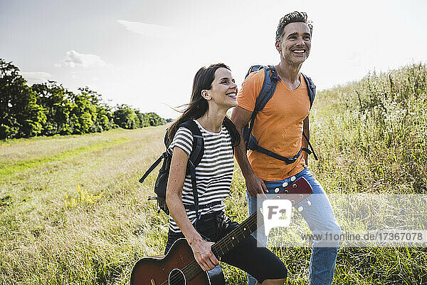 Frau hält Gitarre beim Wandern mit Mann im Gras