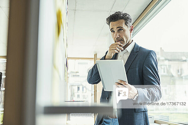 Businessman with digital tablet looking at whiteboard