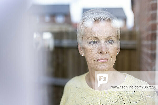 Mature woman contemplating while looking through window