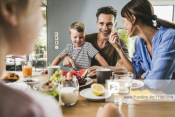Glückliche Familie isst Früchte beim Frühstück zu Hause
