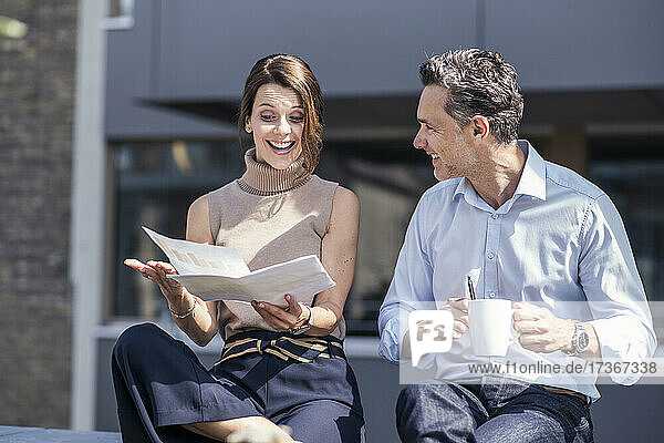 Businesswoman showing document to colleague during sunny day