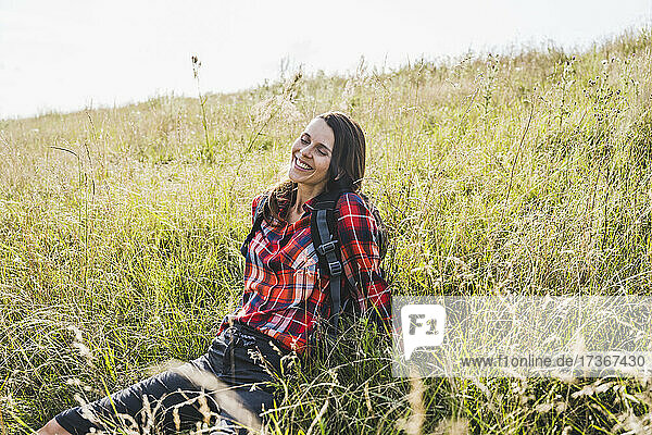 Smiling woman relaxing while sitting on meadow