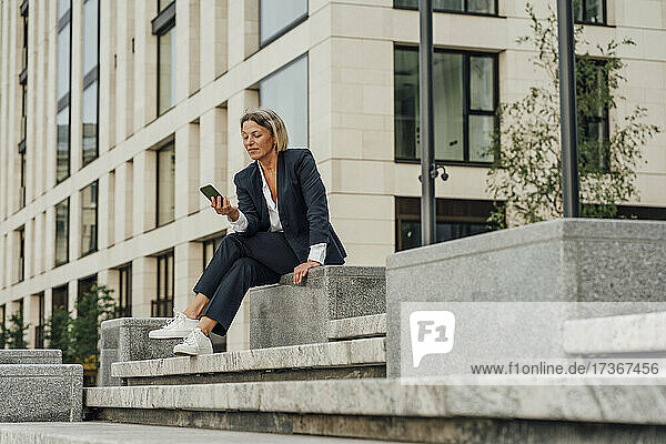 Businesswoman using mobile phone while sitting on steps