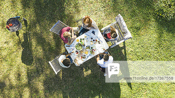 Glückliche junge Freunde beim Essen an einem Tisch im Garten