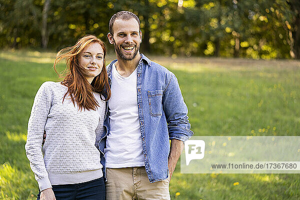 Porträt eines lächelnden jungen Paares bei einem Spaziergang in einem Park