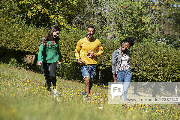 Lächelnde junge Freunde haben Spaß beim Spaziergang im öffentlichen Park