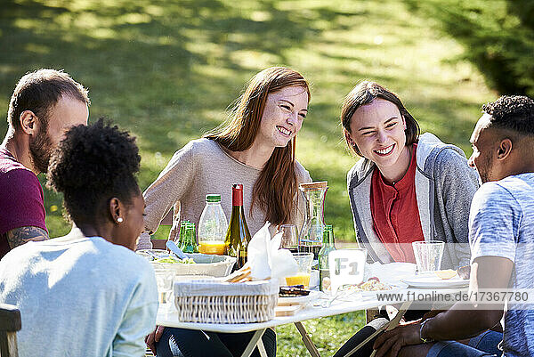 Lächelnde junge Freunde  die im Park das Essen genießen