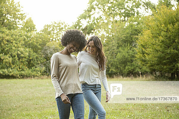 Smiling young female friends walking in park