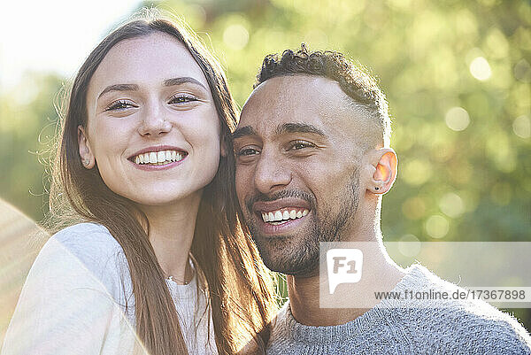 Lächelndes junges Paar  das im öffentlichen Park wegschaut