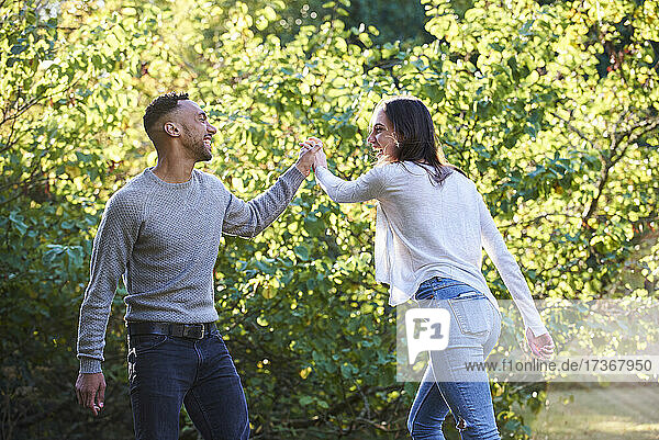 Lächelndes junges Paar tanzt im öffentlichen Park