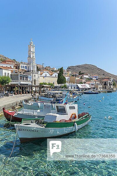 Fischerboote im Hafen von Chalki mit türkisblauem Wasser  Promenade mit bunten Häusern des Ortes Chalki  Chalki  Dodekanes  Griechenland  Europa