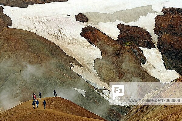 Menschen auf einem Wanderweg vor Schneefeldern  Geothermale Landschaften und Dampf heißer Quellen  Kerlingarfjell  Island  Europa