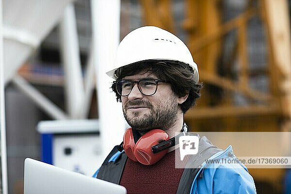 Young engineer wearing a helmet and hearing protection at a work site outside on a construction site  Freiburg  Baden-Württemberg  Germany  Europe