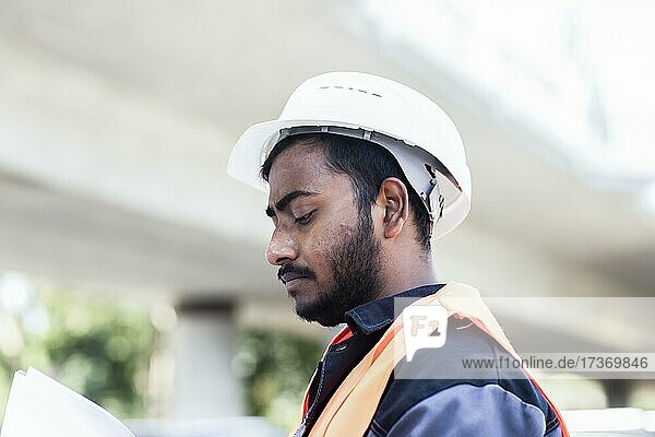 Young technician with beard outside with helmet workingenda on a bridge  Baden-Württemberg  Germany  Europe