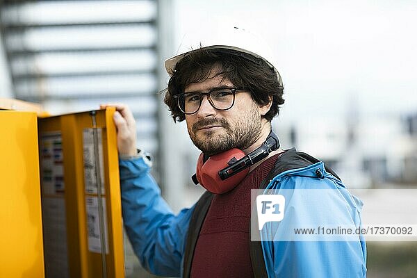 Young engineer with helmet and hearing protection checks outside work with laptop  Freiburg  Baden-Württemberg  Germany  Europe