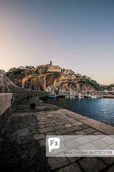 Ein kleiner Hafen am Meer, mit kleinem Bergdorf von der Sonne angestrahlt, Vrbnik, Insel, Krk, Kroatien, Europa