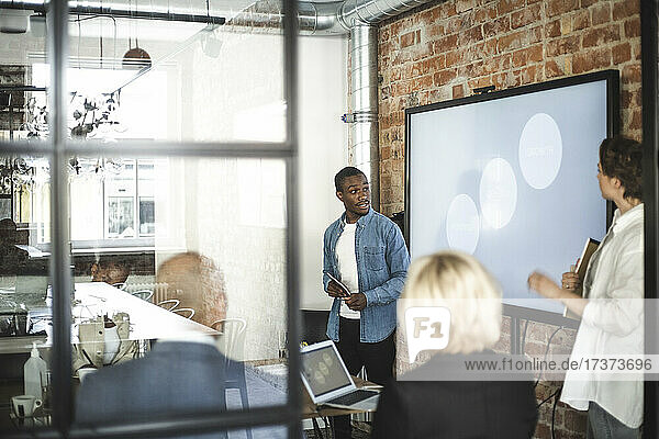Businessman giving presentation to male and female investors in office