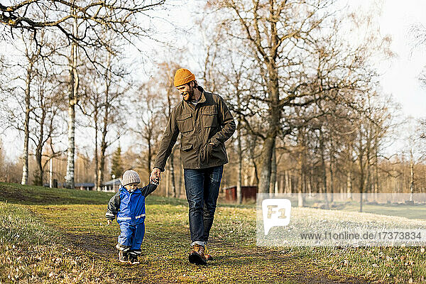 Full length of father and son holding hands while walking at park