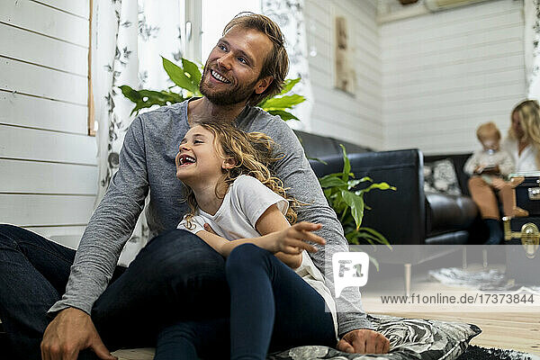 Cheerful daughter sitting with father in living room at home