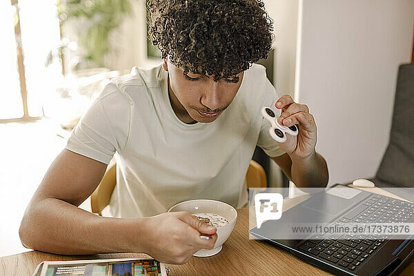 Jugendlicher Junge beim Essen am Tisch im Wohnzimmer sitzend