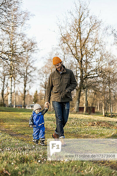 Full length of father father and son holding hands while walking together at park