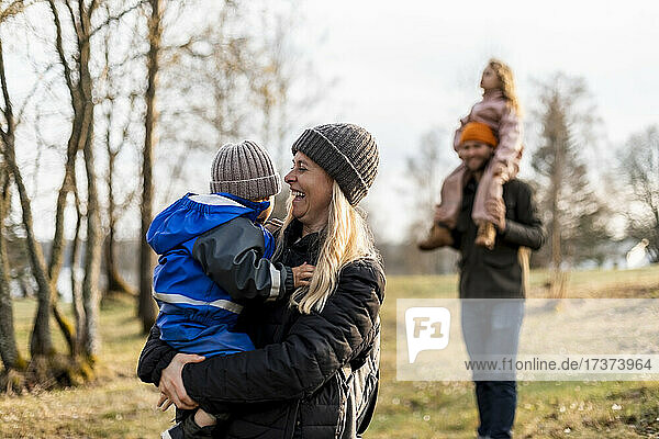 Fröhliche Mutter mit ihrem Sohn im Park stehend