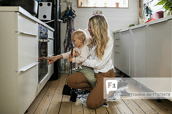 Frau zeigt ihrem Sohn in der Küche zu Hause den Ofen