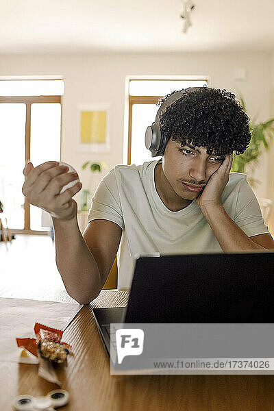 Männlicher Teenager  der einen Laptop benutzt  während er zu Hause sitzt