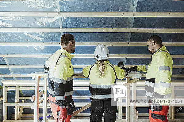 Weibliche Bauunternehmerin diskutiert mit männlichen Kollegen über einen Grundriss am Tisch