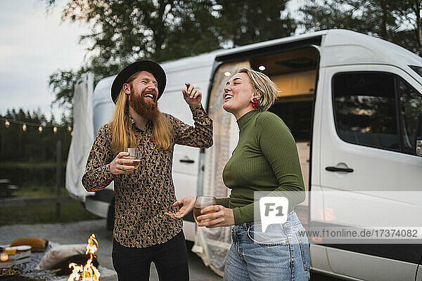 Glückliches junges Paar tanzt abends am Campingwagen
