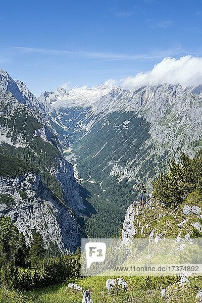 Wanderer blickt in die Kamera  Ausblick ins Reintal  hinten Gipfel der Zugspitze und Alpspitze mit Zugspitzplatt  Wanderweg zur Meilerhütte  Wettersteingebirge  Garmisch Partenkirchen  Bayern  Deutschland  Europa