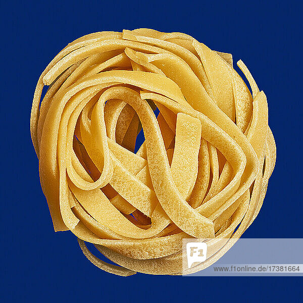 Close up ungekochte Spaghetti Nudeln Nest auf blauem Hintergrund