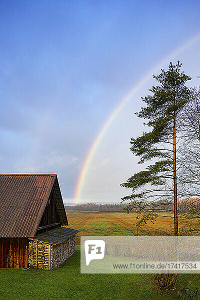 Rural scene  a rainbow in the sky over a barn  after rain.