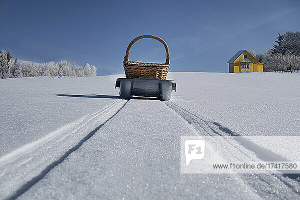 Schlitten  der einen Korb über eine hügelige  verschneite Winterlandschaft transportiert  Estland
