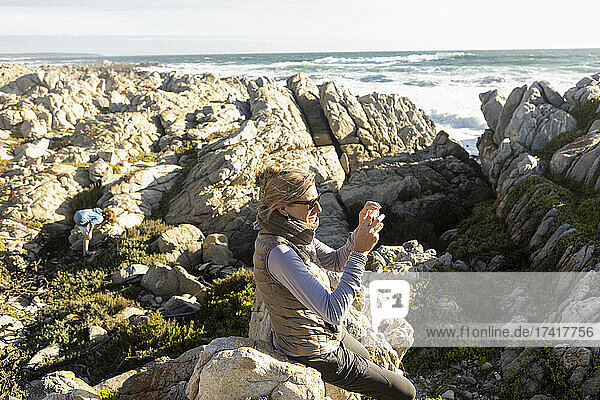 Frau an der Küste  die mit einer Kamera fotografiert