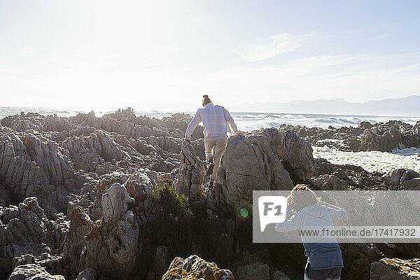 Two children exploring the jagged rocks and rock pools on the Atlantic Ocean coastline