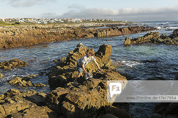 A young boy exploring the rock pools on a jagged rocky Atlantic Ocean coastline