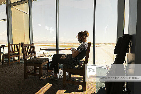 Teenager-Mädchen  das in einer Flughafen-Lounge sitzt und auf ihr Smartphone wartet  Botswana.
